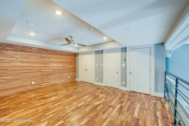 415 E Market St Unit 104, Louisville, KY 40202 - unfurnished bedroom with light wood-type flooring, a tray ceiling, recessed lighting, two closets, and wood walls