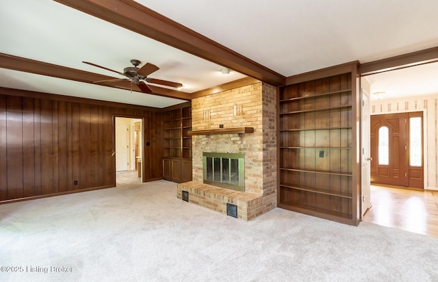 606 N Arbor Dr, Louisville, KY 40223 - unfurnished living room with beam ceiling, wood walls, carpet, a ceiling fan, and a fireplace