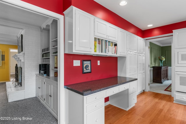 3012 Hayfield Dr, Louisville, KY 40205 - kitchen featuring built in desk, white cabinetry, white oven, dark countertops, and ornamental molding
