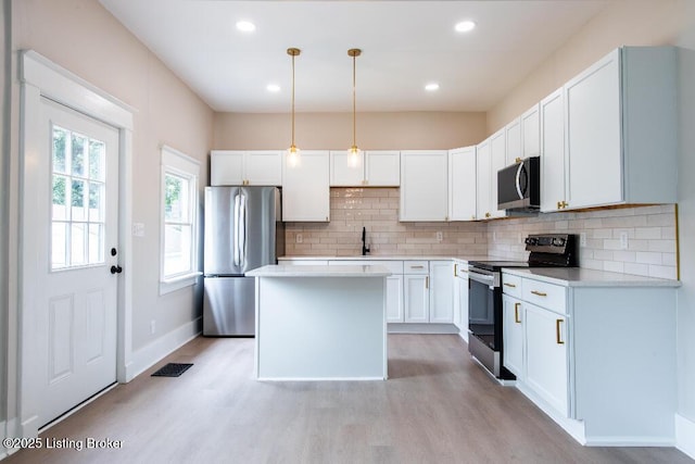 412 Gwendolyn St, Louisville, KY 40203 - kitchen with appliances with stainless steel finishes, light wood-style floors, decorative backsplash, a kitchen island, and recessed lighting