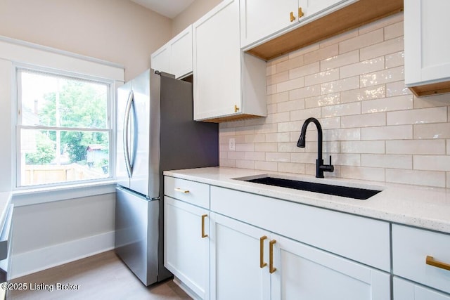 412 Gwendolyn St, Louisville, KY 40203 - kitchen featuring backsplash, white cabinets, light stone counters, and freestanding refrigerator