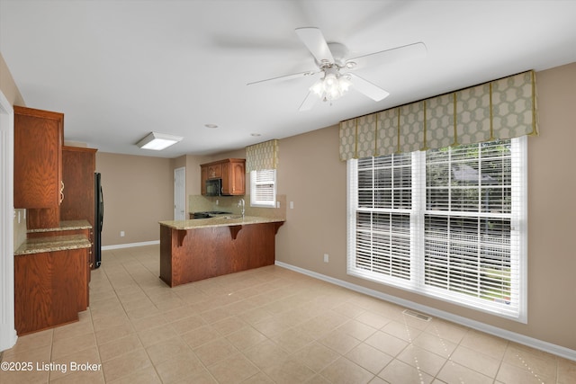 7728 Cottage Cove Way, Louisville, KY 40214 - kitchen featuring black appliances, brown cabinets, light stone countertops, ceiling fan, and a peninsula