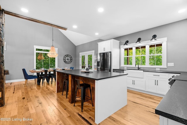 422 Lilac Ln, Cub Run, KY 42729 - kitchen with stainless steel refrigerator with ice dispenser, dark countertops, white cabinetry, a breakfast bar, and vaulted ceiling