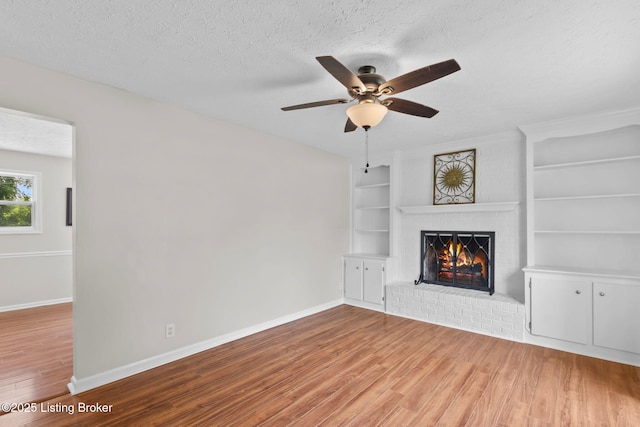 6818 Village Green Blvd, Pewee Valley, KY 40056 - unfurnished living room featuring wood finished floors, built in shelves, a brick fireplace, ceiling fan, and a textured ceiling