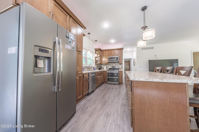 164 Greenshores Circle Ln, Mcdaniels, KY 40152 - kitchen with appliances with stainless steel finishes, a center island, a breakfast bar, light wood-style flooring, and light countertops