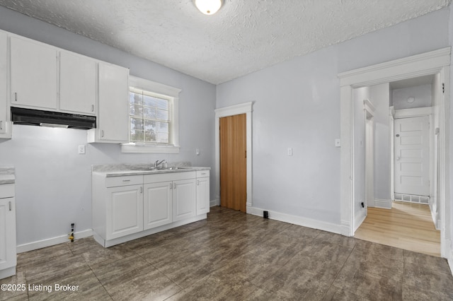 1373 Cypress St, Louisville, KY 40211 - kitchen featuring under cabinet range hood, white cabinets, light countertops, a textured ceiling, and wood finished floors