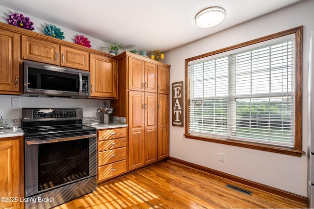 309 Clarks Ln, Clarkson, KY 42726 - kitchen with stainless steel microwave, range with electric cooktop, light countertops, light wood-style floors, and brown cabinets
