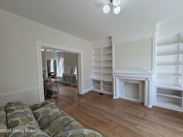 1403 S Brook St, Louisville, KY 40208 - unfurnished living room featuring wood finished floors, a fireplace, built in features, and a chandelier