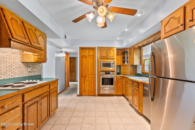 7502 Sam Ct, Louisville, KY 40214 - kitchen with stainless steel appliances, brown cabinetry, ceiling fan, decorative backsplash, and light tile patterned flooring