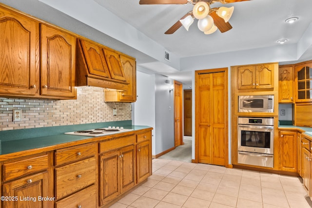 7502 Sam Ct, Louisville, KY 40214 - kitchen with stainless steel appliances, a warming drawer, brown cabinetry, ceiling fan, and custom exhaust hood