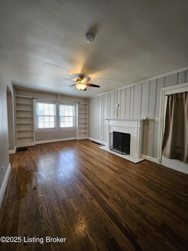 3919 Staebler Ave, Louisville, KY 40207 - unfurnished living room with built in shelves, a ceiling fan, a brick fireplace, and dark wood-style flooring