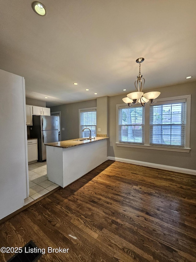 3919 Staebler Ave, Louisville, KY 40207 - kitchen with freestanding refrigerator, a peninsula, light wood-style floors, white cabinetry, and a chandelier