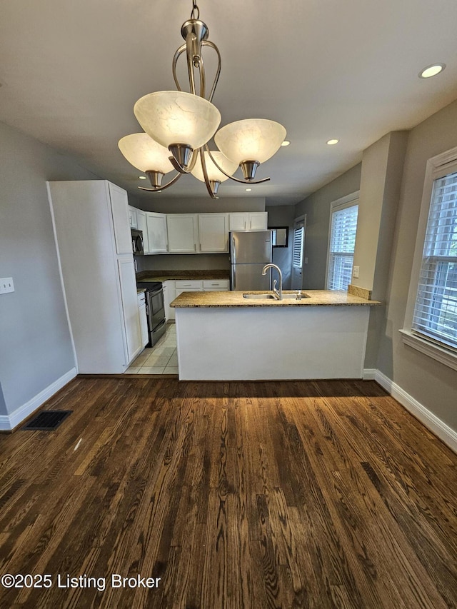 3919 Staebler Ave, Louisville, KY 40207 - kitchen with electric stove, freestanding refrigerator, white cabinets, a peninsula, and wood finished floors