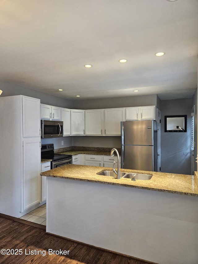 3919 Staebler Ave, Louisville, KY 40207 - kitchen with stainless steel appliances, white cabinetry, light stone counters, recessed lighting, and light wood-style floors