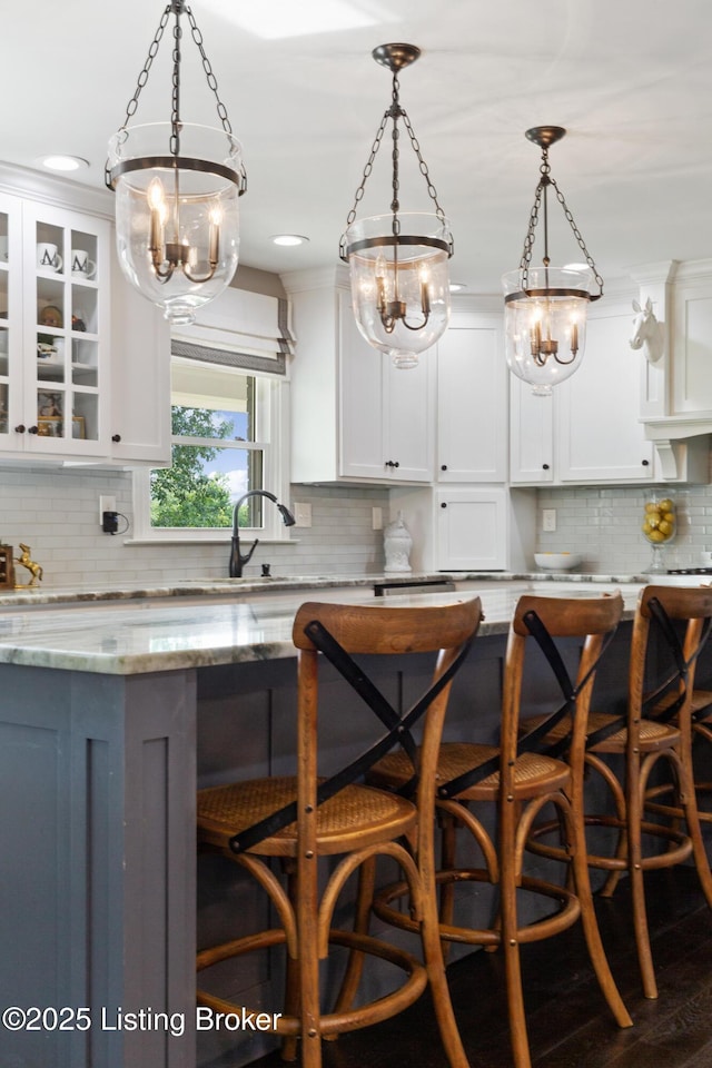 10020 Oak Grove Rd, Louisville, KY 40291 - kitchen featuring a kitchen bar, backsplash, white cabinetry, a chandelier, and hanging light fixtures