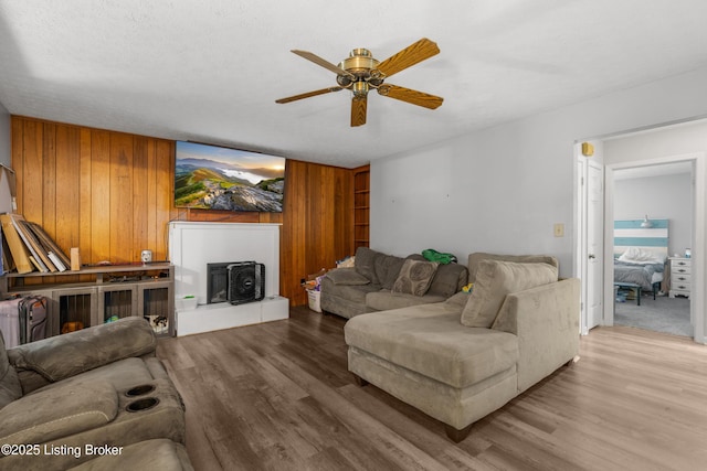 2625 Shumate Rd, Ekron, KY 40117 - living area with ceiling fan, wooden walls, wood finished floors, and a fireplace with raised hearth
