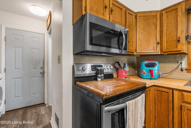 2625 Shumate Rd, Ekron, KY 40117 - kitchen featuring stainless steel appliances, brown cabinets, light wood finished floors, and stacked washer / drying machine