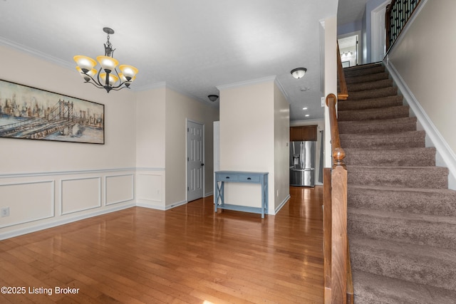 10008 Hornbeam Blvd, Louisville, KY 40228 - stairway featuring wood finished floors, a chandelier, ornamental molding, and wainscoting