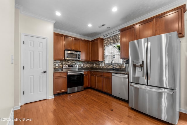10008 Hornbeam Blvd, Louisville, KY 40228 - kitchen with appliances with stainless steel finishes, dark countertops, ornamental molding, tasteful backsplash, and wood-type flooring
