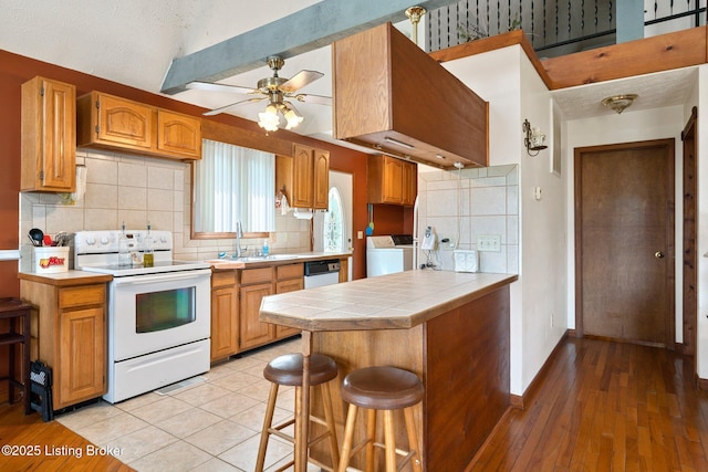 4333 Wax Rd, Clarkson, KY 42726 - kitchen with white appliances, tile counters, a ceiling fan, washer and clothes dryer, and a kitchen breakfast bar