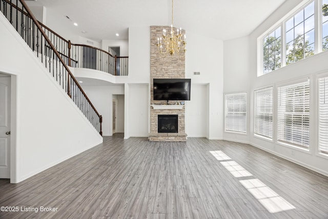 14433 Halden Ridge Way, Louisville, KY 40245 - unfurnished living room featuring a towering ceiling, stairs, a chandelier, wood finished floors, and a stone fireplace