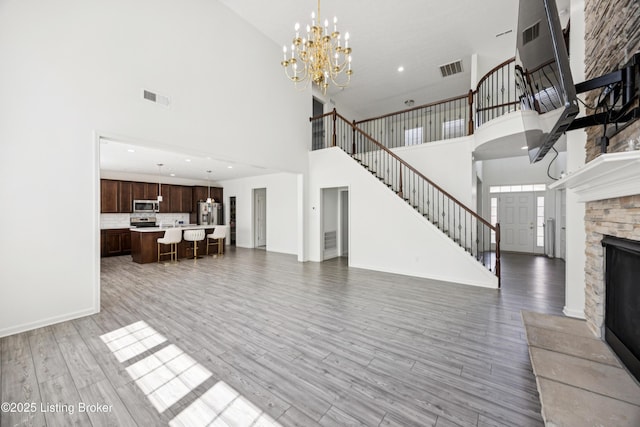 14433 Halden Ridge Way, Louisville, KY 40245 - unfurnished living room with a high ceiling, a chandelier, stairway, a stone fireplace, and light wood-style floors