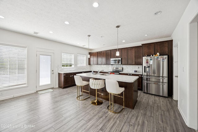 14433 Halden Ridge Way, Louisville, KY 40245 - kitchen with stainless steel appliances, light countertops, a breakfast bar, decorative backsplash, and an island with sink