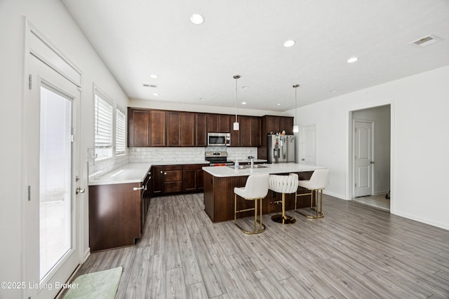 14433 Halden Ridge Way, Louisville, KY 40245 - kitchen featuring stainless steel appliances, a kitchen breakfast bar, light countertops, decorative backsplash, and an island with sink
