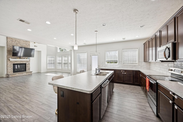 14433 Halden Ridge Way, Louisville, KY 40245 - kitchen with stainless steel appliances, a center island with sink, plenty of natural light, light wood-style flooring, and a textured ceiling