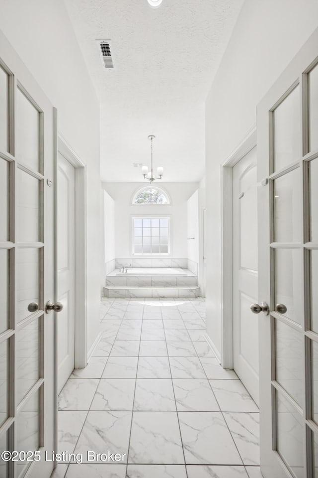 14433 Halden Ridge Way, Louisville, KY 40245 - hallway with light marble finish flooring, a chandelier, and a textured ceiling