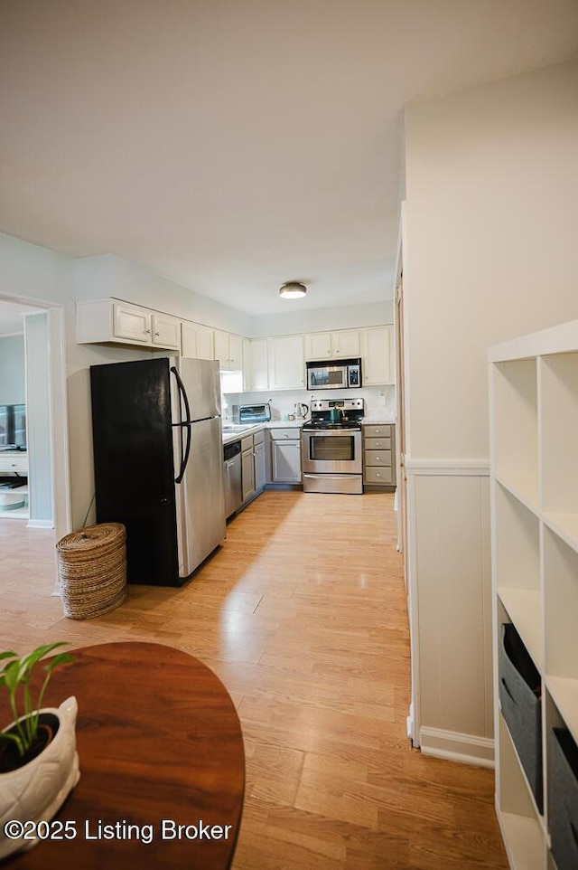 6812 Holly Lake Dr, Louisville, KY 40291 - kitchen featuring stainless steel appliances, white cabinets, light wood finished floors, light countertops, and a wainscoted wall