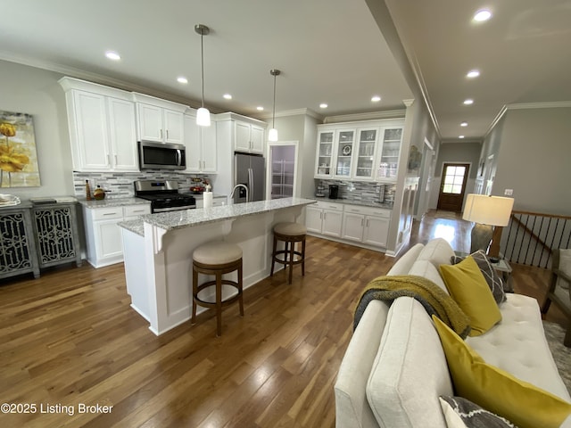 7508 Pavilion Park Rd, Louisville, KY 40214 - kitchen with stainless steel appliances, decorative backsplash, white cabinets, a kitchen island with sink, and ornamental molding