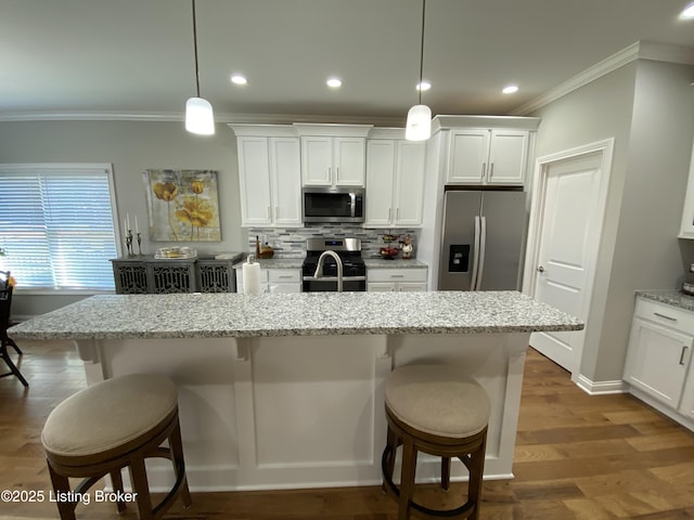 7508 Pavilion Park Rd, Louisville, KY 40214 - kitchen with stainless steel appliances, crown molding, a breakfast bar area, white cabinets, and an island with sink
