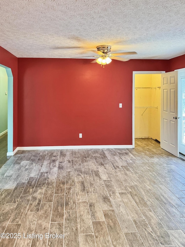599 Ritchie Dr, Brandenburg, KY 40108 - empty room featuring arched walkways, wood finished floors, a ceiling fan, and a textured ceiling