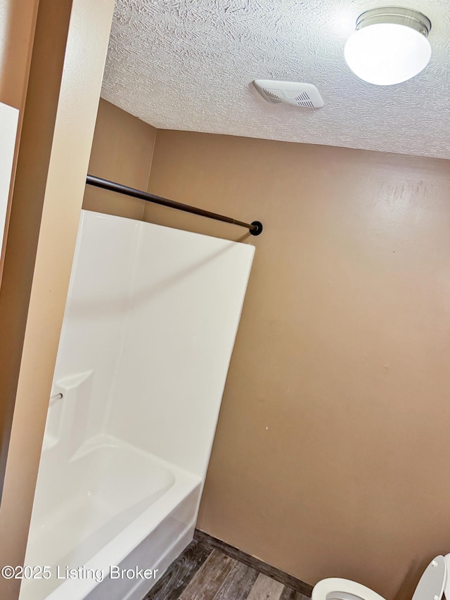 599 Ritchie Dr, Brandenburg, KY 40108 - bathroom with wood finished floors, a textured ceiling, and bathtub / shower combination