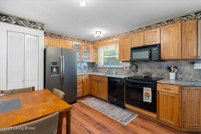3706 Glenlea Way, Jeffersontown, KY 40299 - kitchen with black appliances, light wood-type flooring, a textured ceiling, decorative backsplash, and glass insert cabinets
