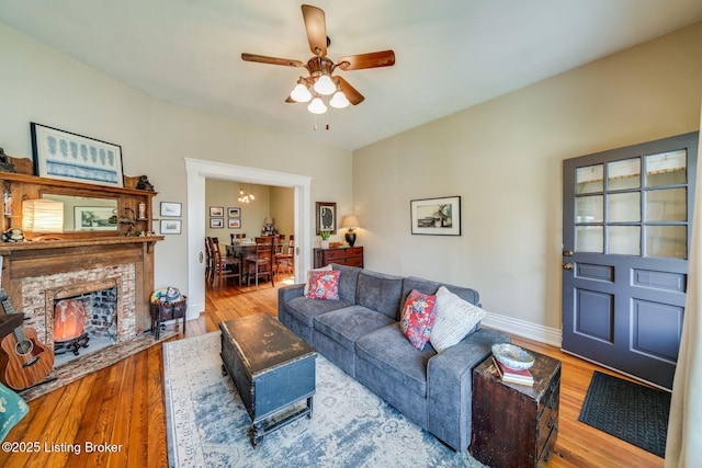 1021 Mulberry St, Louisville, KY 40217 - living area featuring wood finished floors, a ceiling fan, a brick fireplace, and a chandelier