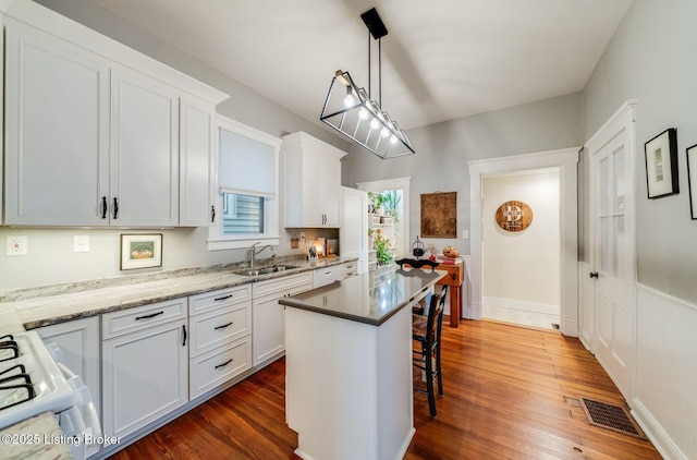 1021 Mulberry St, Louisville, KY 40217 - kitchen with a kitchen breakfast bar, dark wood-style floors, white cabinetry, range, and a kitchen island