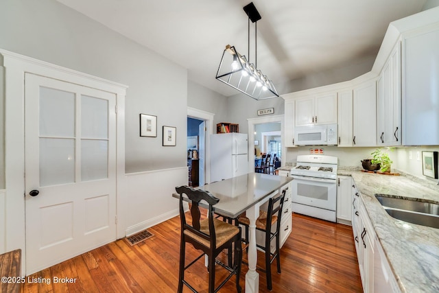 1021 Mulberry St, Louisville, KY 40217 - kitchen with white appliances, hardwood / wood-style flooring, white cabinetry, light stone countertops, and wainscoting