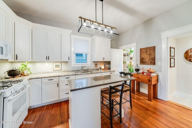 1021 Mulberry St, Louisville, KY 40217 - kitchen featuring white appliances, a kitchen breakfast bar, dark wood-type flooring, and white cabinets