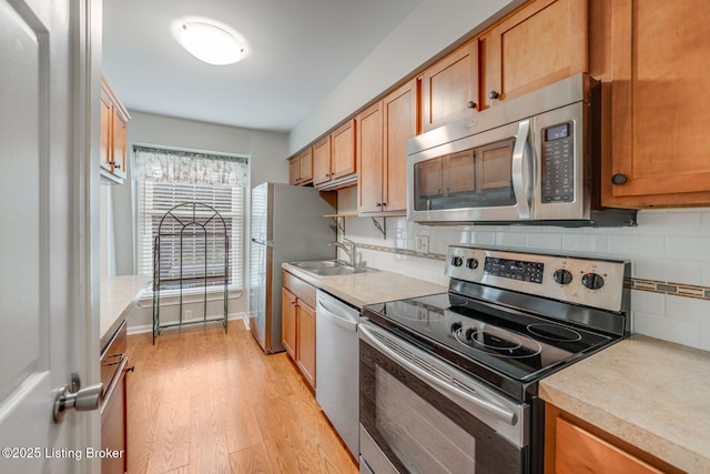 521 Zorn Ave Apt G8, Louisville, KY 40206 - kitchen featuring stainless steel appliances, light wood-type flooring, light countertops, tasteful backsplash, and brown cabinetry