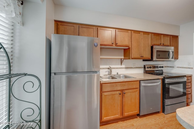 521 Zorn Ave Apt G8, Louisville, KY 40206 - kitchen featuring appliances with stainless steel finishes, tasteful backsplash, light countertops, light wood-style flooring, and brown cabinets