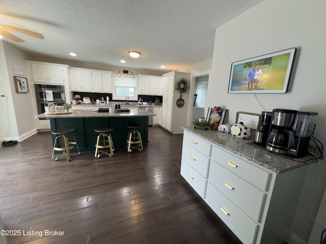173 Megan Way, Falls Of Rough, KY 40119 - kitchen with double oven, a breakfast bar, white cabinets, dark wood-style flooring, and a textured ceiling