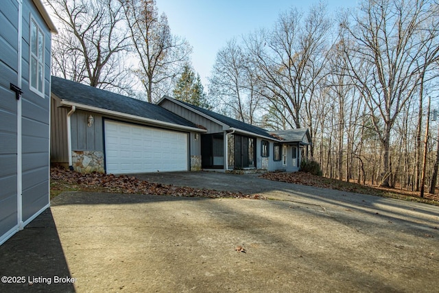 41 Raspberry Ct, Brandenburg, KY 40108 - view of front of property featuring an attached garage, driveway, board and batten siding, stone siding, and roof with shingles