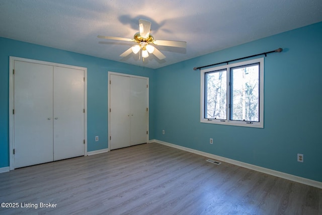 41 Raspberry Ct, Brandenburg, KY 40108 - unfurnished bedroom featuring wood finished floors, ceiling fan, and two closets