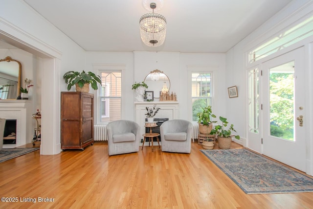 1211 Everett Ave, Louisville, KY 40204 - foyer entrance featuring a brick fireplace, radiator, wood finished floors, and a chandelier