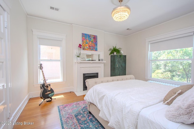 1211 Everett Ave, Louisville, KY 40204 - bedroom with multiple windows, light wood-type flooring, a brick fireplace, ornamental molding, and a chandelier