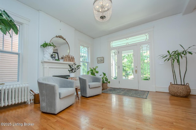 1211 Everett Ave, Louisville, KY 40204 - foyer entrance featuring radiator heating unit, a brick fireplace, a chandelier, and wood finished floors