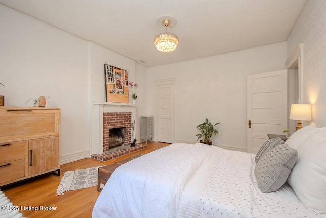 1211 Everett Ave, Louisville, KY 40204 - bedroom with light wood-style flooring, a brick fireplace, and a chandelier