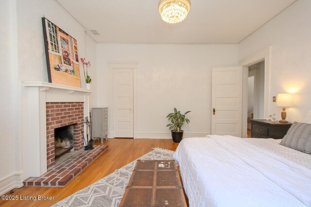 1211 Everett Ave, Louisville, KY 40204 - bedroom with wood finished floors, a chandelier, and a brick fireplace